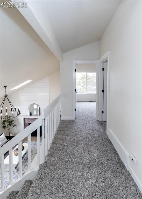 corridor with vaulted ceiling, carpet floors, and a notable chandelier