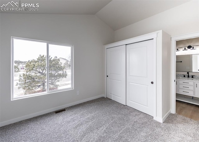 unfurnished bedroom with lofted ceiling, sink, carpet, and a closet