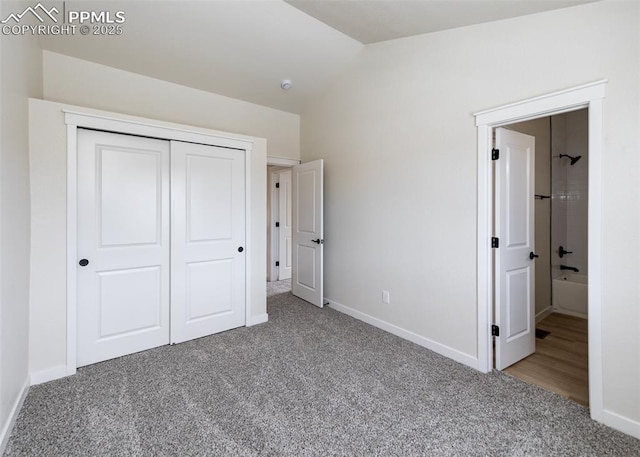 unfurnished bedroom with vaulted ceiling, carpet, and a closet