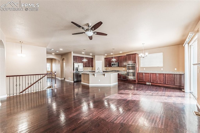 unfurnished living room featuring sink, ceiling fan with notable chandelier, dark wood-type flooring, and a textured ceiling