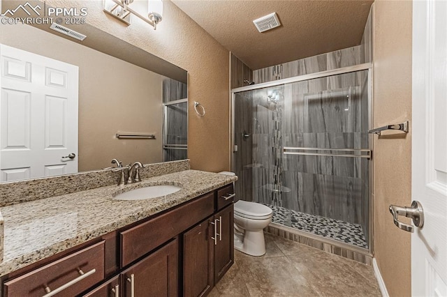 bathroom with tile patterned floors, toilet, a shower with shower door, a textured ceiling, and vanity