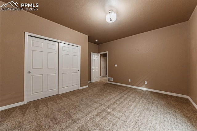 unfurnished bedroom featuring carpet floors, a textured ceiling, and a closet