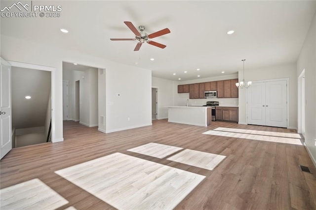 unfurnished living room with sink, ceiling fan with notable chandelier, and light hardwood / wood-style floors