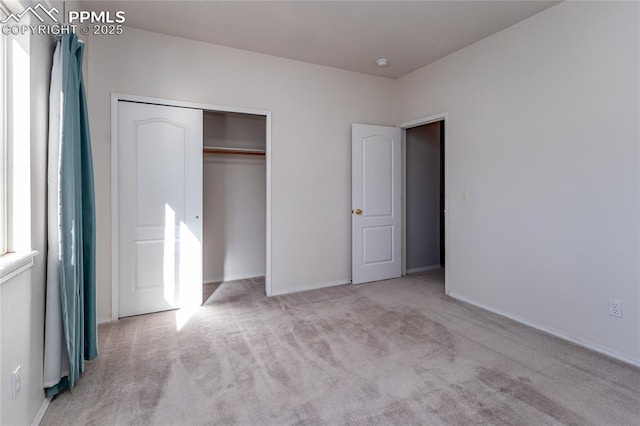 unfurnished bedroom with light colored carpet and a closet