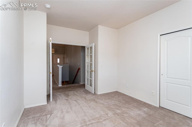 empty room with light carpet and a textured ceiling