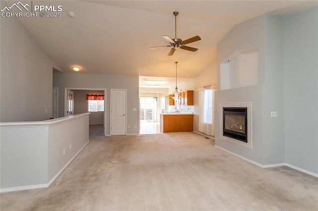 unfurnished living room featuring a tile fireplace, vaulted ceiling, light carpet, and ceiling fan