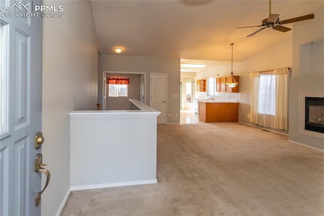 unfurnished living room featuring lofted ceiling, light colored carpet, and ceiling fan