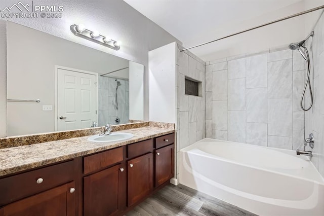 bathroom featuring hardwood / wood-style flooring, vanity, and tiled shower / bath combo