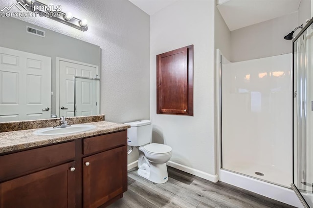 bathroom featuring hardwood / wood-style flooring, vanity, an enclosed shower, and toilet