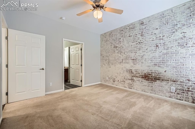 unfurnished bedroom featuring connected bathroom, ceiling fan, brick wall, and carpet