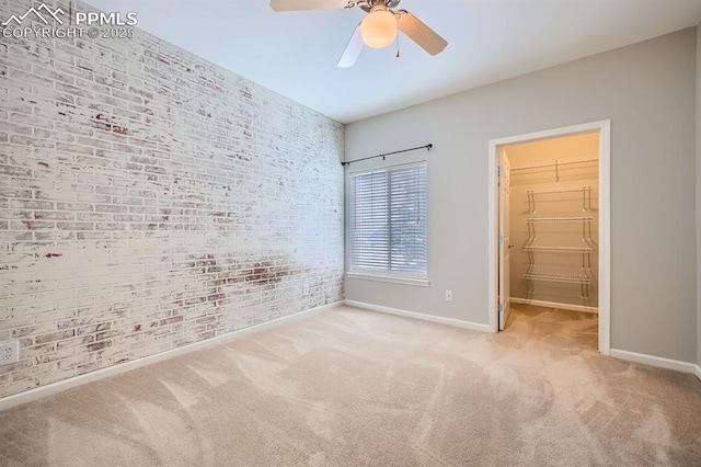 carpeted empty room with brick wall and ceiling fan