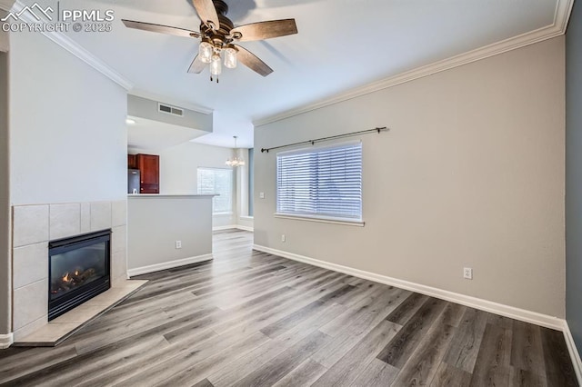 unfurnished living room with hardwood / wood-style floors, crown molding, ceiling fan with notable chandelier, and a fireplace