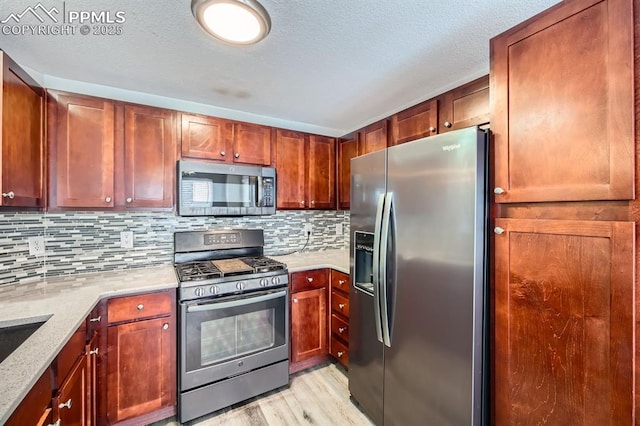 kitchen with tasteful backsplash, light hardwood / wood-style flooring, a textured ceiling, appliances with stainless steel finishes, and light stone countertops