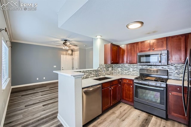 kitchen with appliances with stainless steel finishes, sink, decorative backsplash, kitchen peninsula, and crown molding