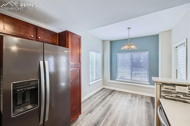 kitchen with stainless steel refrigerator with ice dispenser, a textured ceiling, a notable chandelier, pendant lighting, and light hardwood / wood-style floors