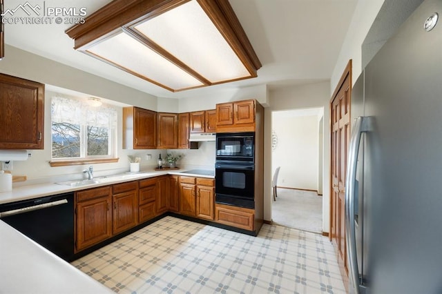 kitchen featuring light floors, under cabinet range hood, a sink, light countertops, and black appliances