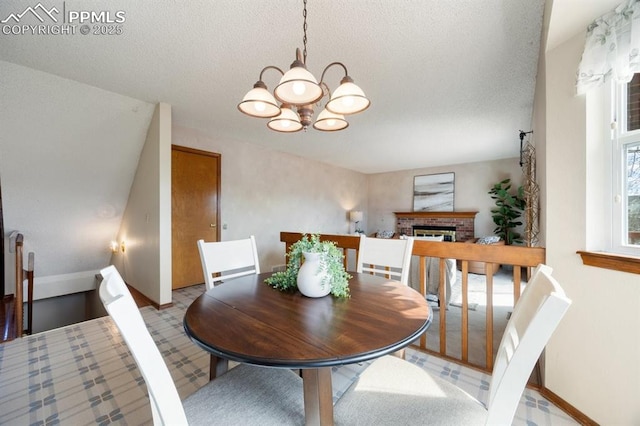 dining space featuring a chandelier, a textured ceiling, a fireplace, and baseboards