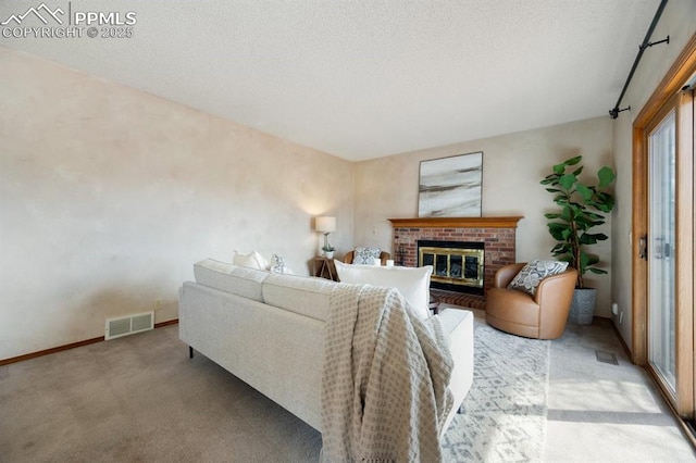 living area featuring baseboards, visible vents, light colored carpet, a textured ceiling, and a brick fireplace