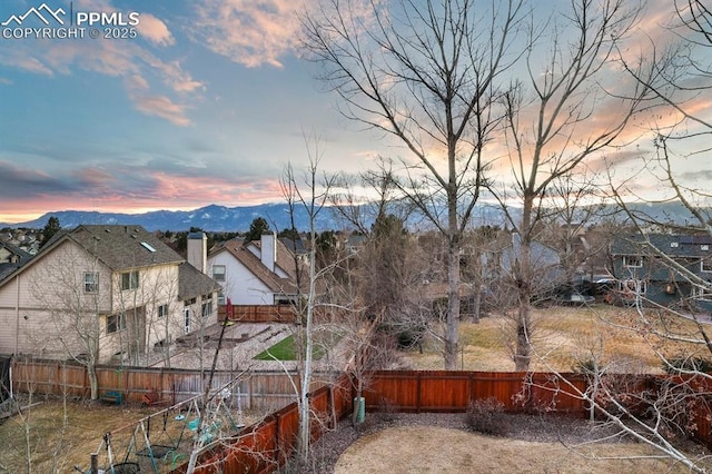 view of yard with a residential view, a fenced backyard, and a mountain view