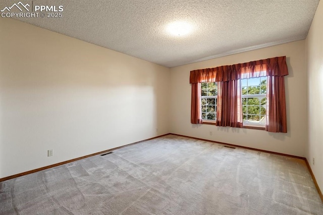 empty room featuring carpet, visible vents, baseboards, and a textured ceiling