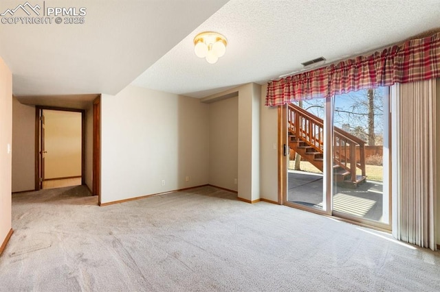 carpeted empty room featuring visible vents, baseboards, and a textured ceiling