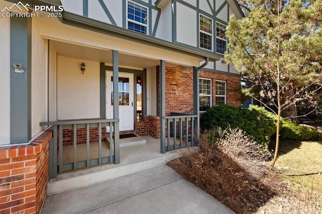 doorway to property with a porch and brick siding