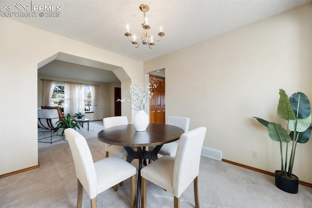 dining area with a chandelier, arched walkways, light colored carpet, and visible vents