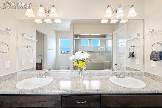 full bath featuring toilet, a stall shower, double vanity, and a sink