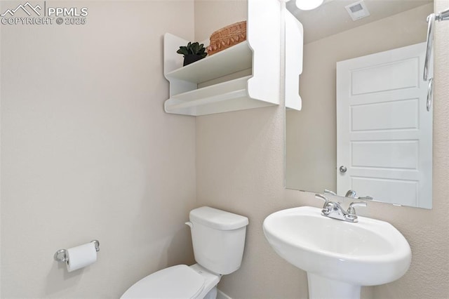 half bath featuring visible vents, a sink, and toilet