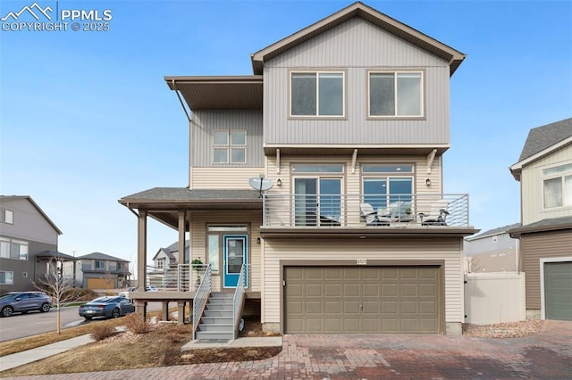 view of front of property with a garage, decorative driveway, fence, and a balcony