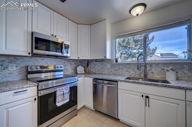 kitchen with sink, stainless steel appliances, white cabinets, and light stone countertops