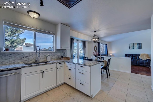 kitchen featuring sink, dishwasher, kitchen peninsula, light stone countertops, and white cabinets