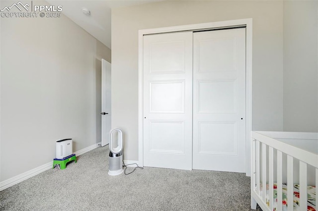 bedroom with a nursery area, carpet flooring, and a closet