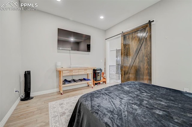 bedroom with a barn door and light wood-type flooring