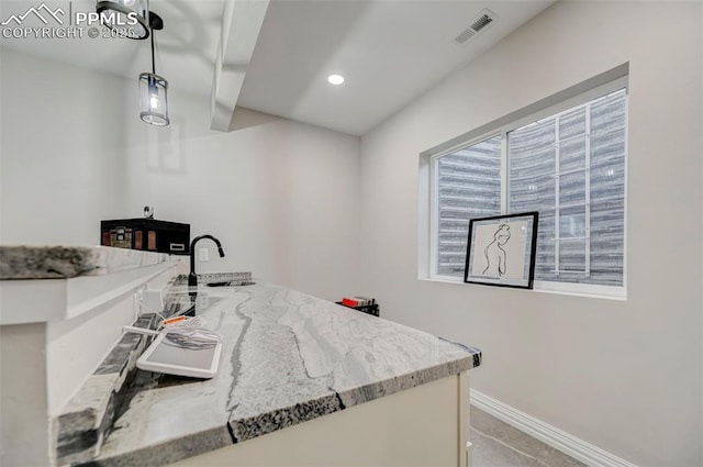 kitchen with sink, decorative light fixtures, and light stone countertops