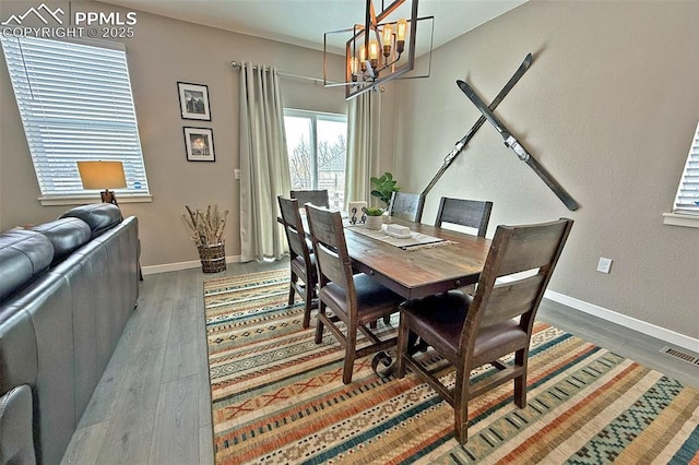 dining space with a chandelier, visible vents, baseboards, and wood finished floors