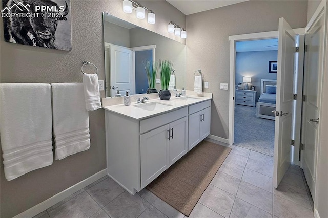 ensuite bathroom featuring double vanity, tile patterned flooring, and a sink