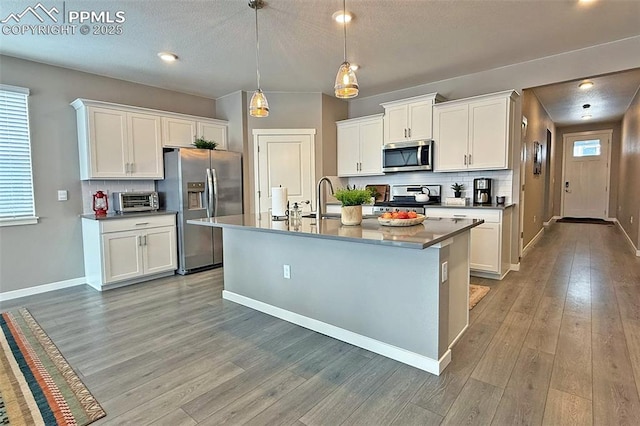 kitchen with light wood finished floors, white cabinetry, appliances with stainless steel finishes, and backsplash