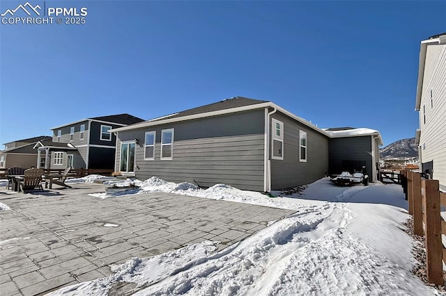 view of snowy exterior featuring a patio area and fence