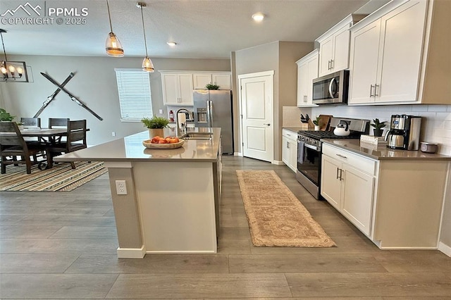 kitchen featuring appliances with stainless steel finishes, dark wood-style flooring, a center island with sink, and tasteful backsplash