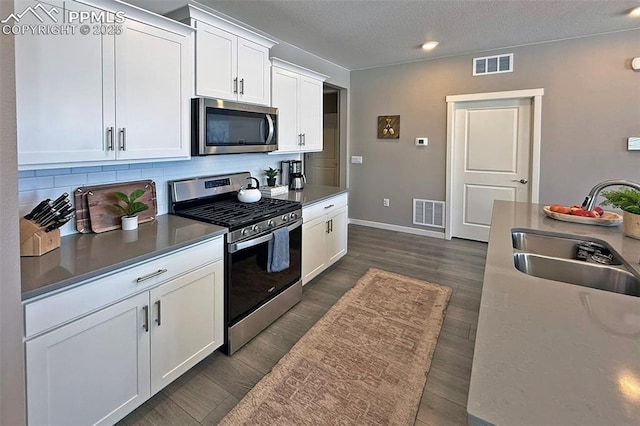 kitchen featuring stainless steel appliances, visible vents, a sink, and tasteful backsplash