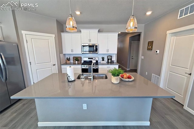 kitchen featuring appliances with stainless steel finishes, wood finished floors, visible vents, and tasteful backsplash