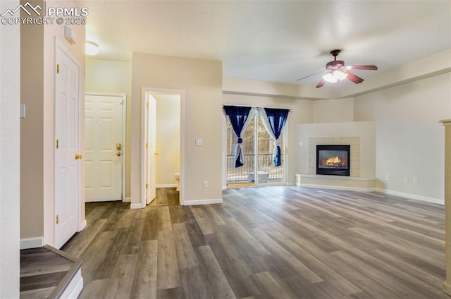 unfurnished living room featuring ceiling fan, wood-type flooring, and a fireplace