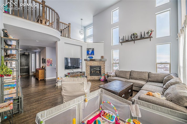 living room featuring a towering ceiling, a fireplace, and dark hardwood / wood-style flooring