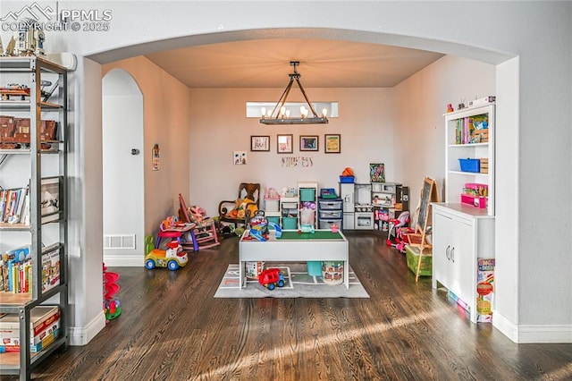 game room with dark hardwood / wood-style flooring and an inviting chandelier