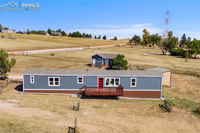 view of front facade featuring a rural view, a storage unit, and a deck