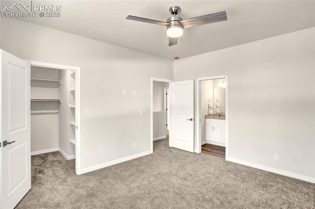 unfurnished bedroom featuring carpet floors, a spacious closet, baseboards, and ensuite bathroom