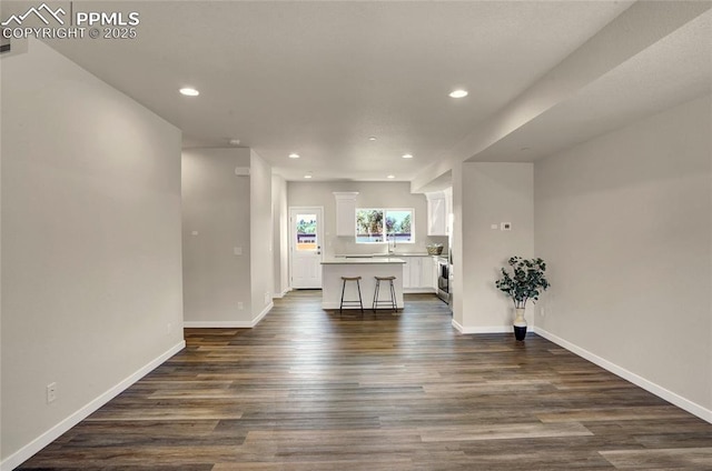 empty room featuring dark wood-type flooring, recessed lighting, and baseboards