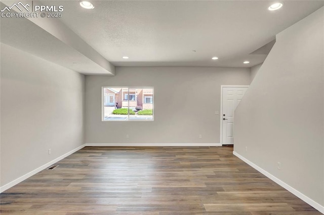 unfurnished room with baseboards, wood finished floors, and recessed lighting