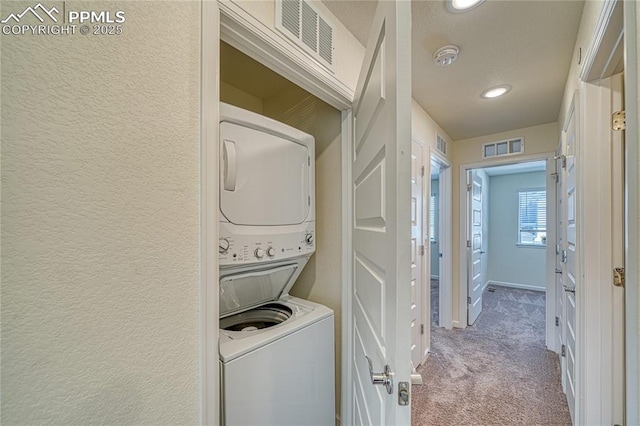 laundry room featuring light colored carpet and stacked washer and clothes dryer